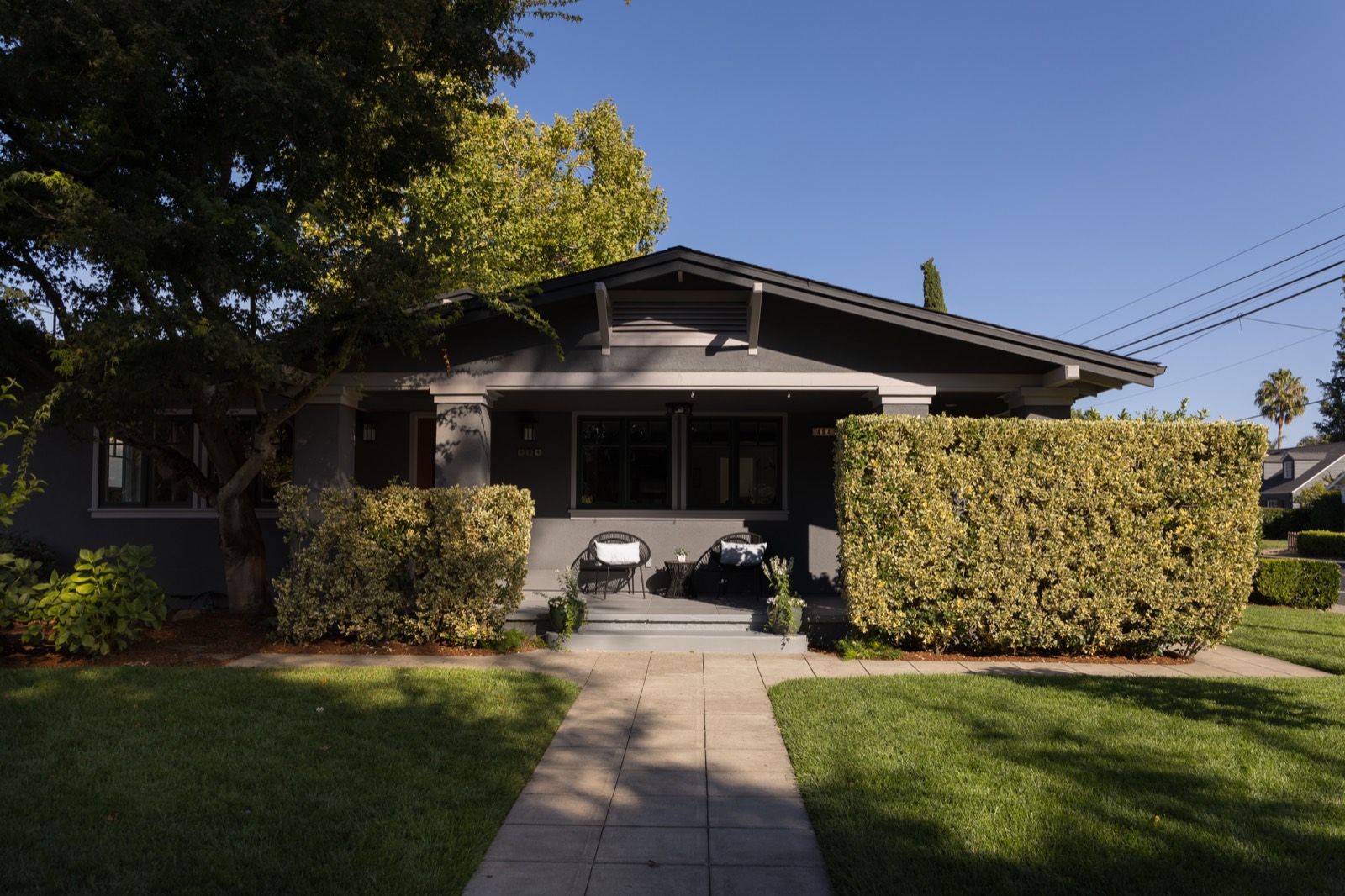 Front of 494 Fourth Street East: Craftsman bungalow with covered porch, hedges and a front lawn
