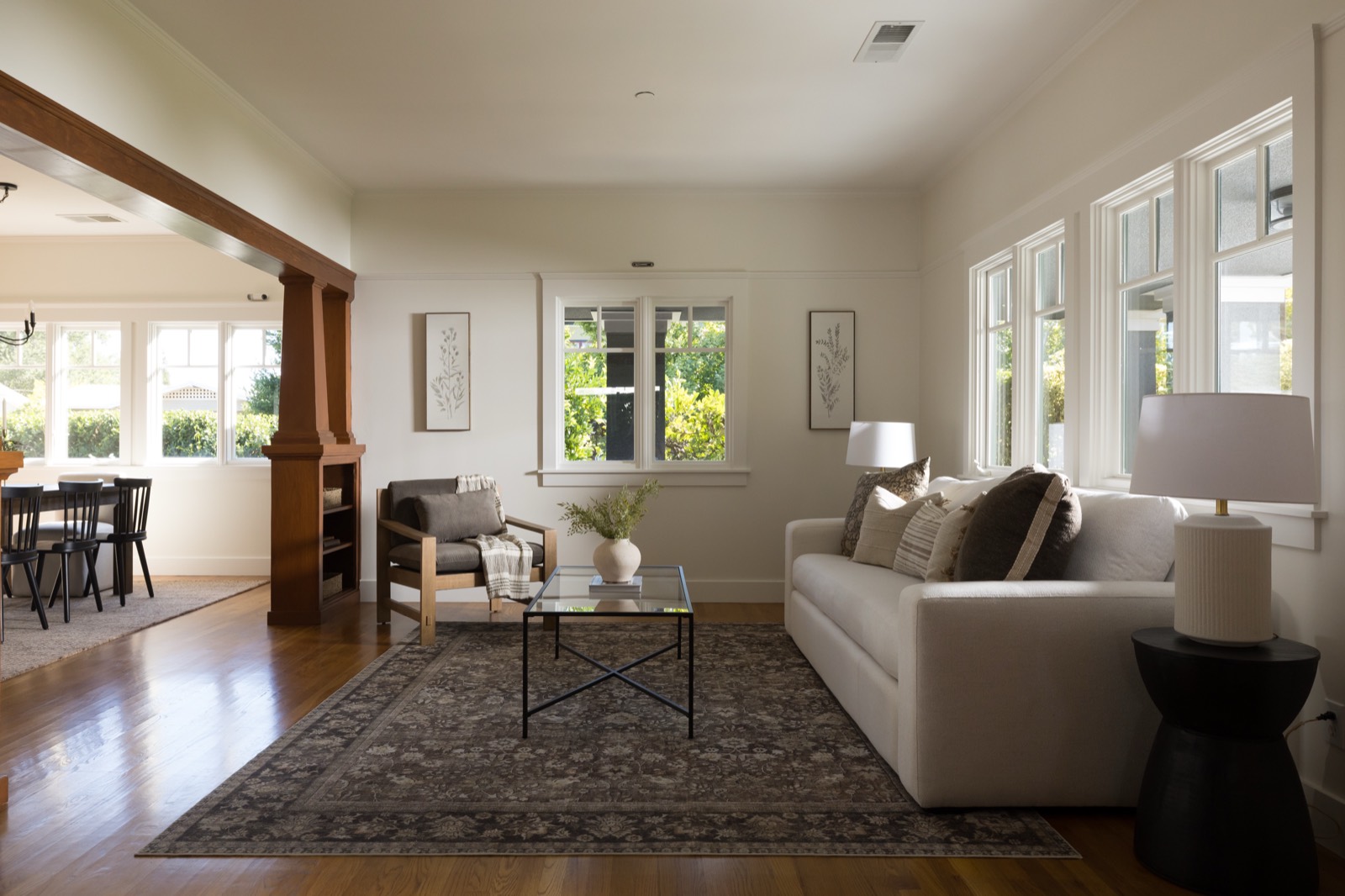 Living room with oak floors, wide window wall and a Craftsman wood column opening to the dining room