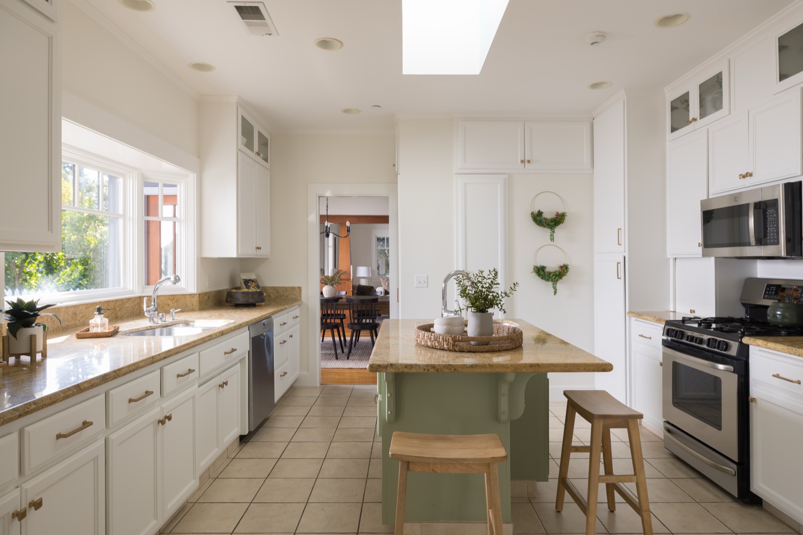 White kitchen with granite counters, a center island and a skylight