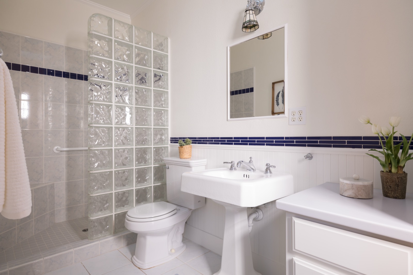 Second bathroom with pedestal sink and glass block shower